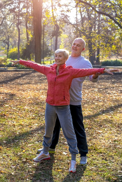 Free photo senior male and a female exercising together in the park in autumn