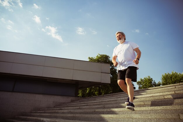 Senior man as runner with armband or fitness tracker at the city's street