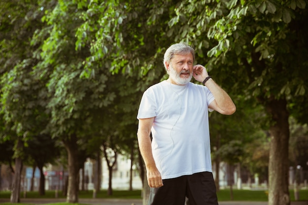 Senior man as runner with fitness tracker at the city's street.