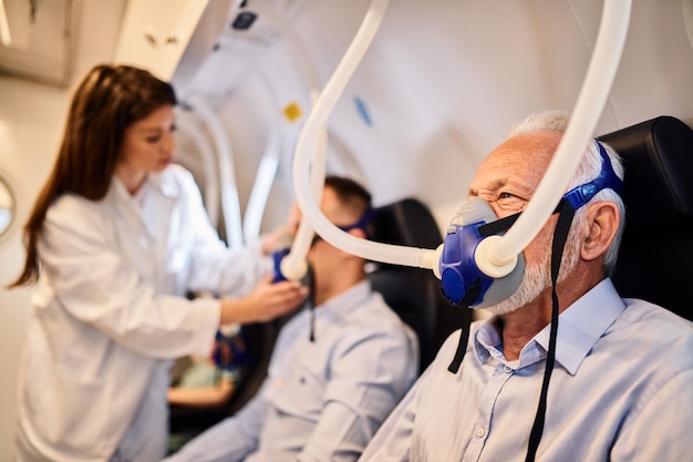 Free photo senior man breathing through mask during oxygen therapy in hyperbaric chamber