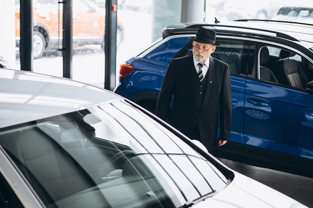 Senior man in a car showroom choosing a car