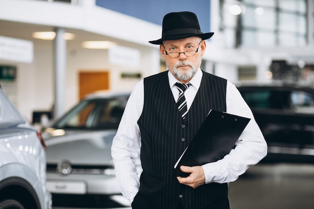 Free photo senior man in a car showroom choosing a car