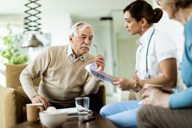 Free photo senior man and healthcare worker going through medical reports during home visit