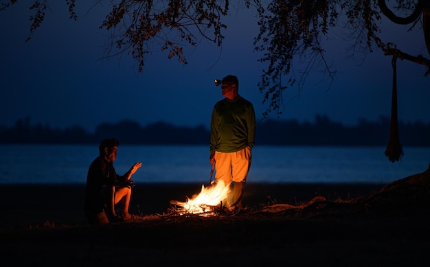 Free photo senior man  and his friend warming his hands with the flames of a bonfire at cold weather in early moring, copy space