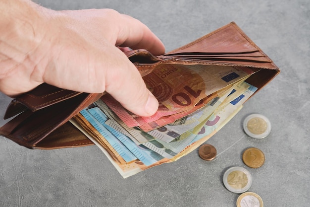 Free photo senior man holds a wallet with euro banknotes in his hand euro banknotes in the wallet wallet with money in a man's hand background idea of paying taxes buying or paying for services