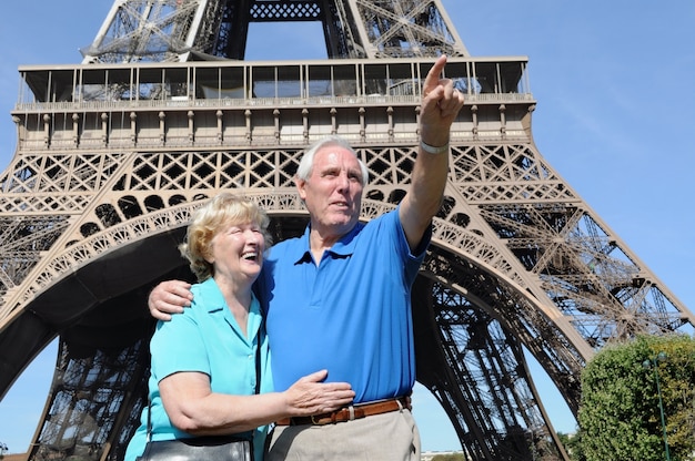 Senior man pointing at something to his wife next to the eiffel tower