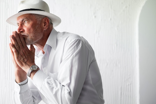 Senior man posing in white shirt and hat