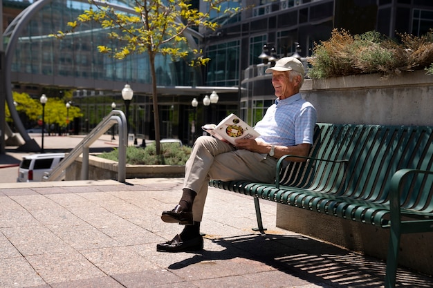 Senior man reading book on bench outdoors