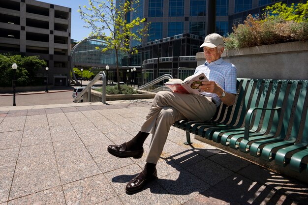 Senior man reading book on bench outdoors