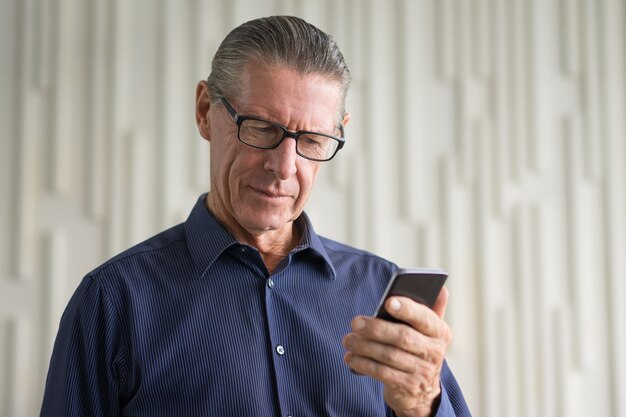 Senior Man Reading Info on Smartphone Screen