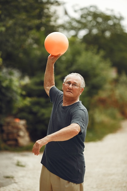 Senior man at summer park. Grangfather using a ball.