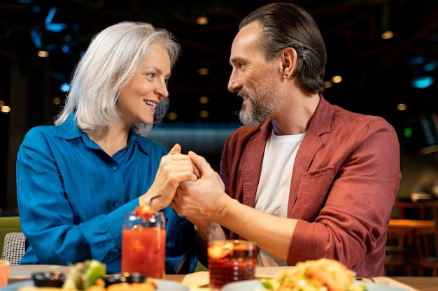 Senior man surprising his friend and holding her hands at a restaurant