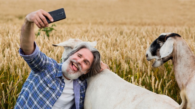 Free photo senior man taking slefie with goat