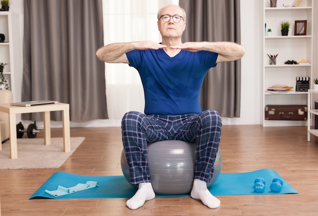 Senior man training on stability ball in living room