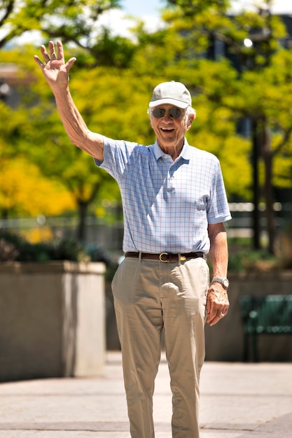 Senior man waving while taking a walk outdoors