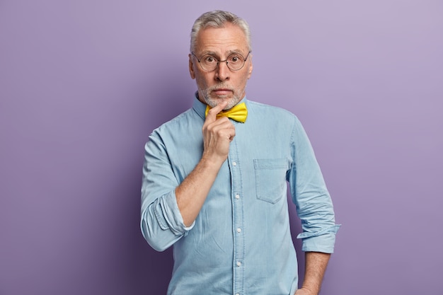 Senior man wearing blue shirt and yellow bowtie