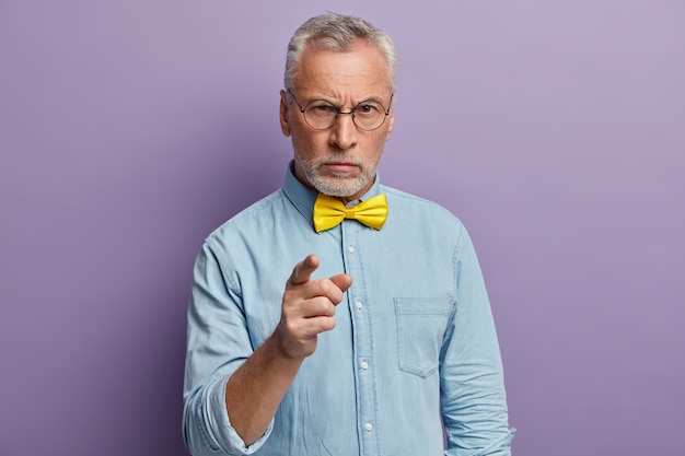 Senior man wearing blue shirt and yellow bowtie