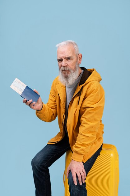 Senior man with passport sitting on baggage