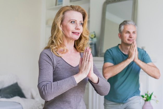 Senior man and woman doing yoga at home