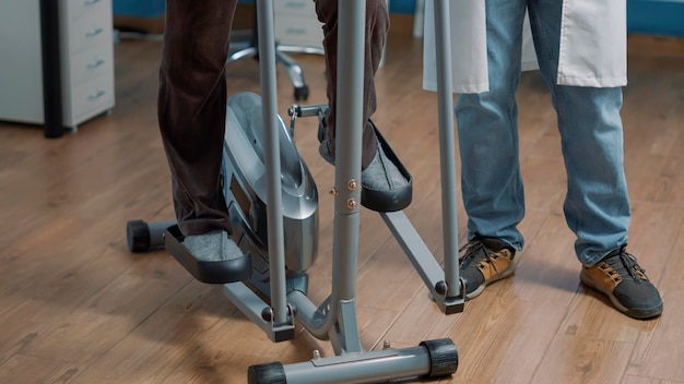 Free photo senior patient doing physiotherapy exercise on wellness bicycle to heal physical injury at rehbailitation consultation, receiving support from male doctor. alternative medicine.