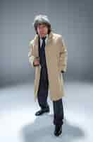 Free photo senior police agent with a gun standing as detective or mafia boss. studio shot on gray in retro stile