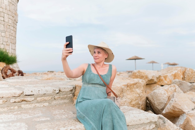 Senior tourist woman with beach hat taking selfie