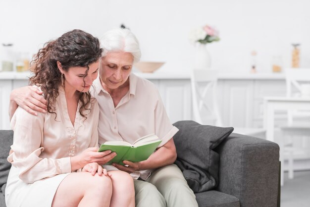 Senior woman and daughter reading books together at home