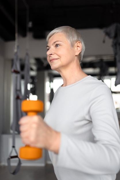 Senior woman doing dumbbells exercises at the gym