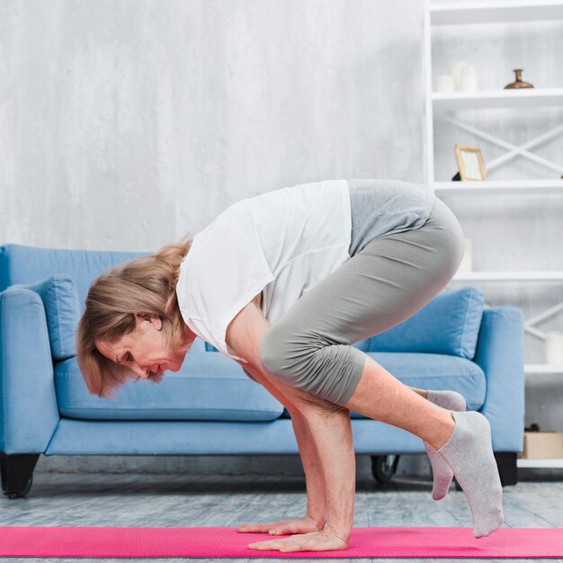 Senior woman doing yoga in living room