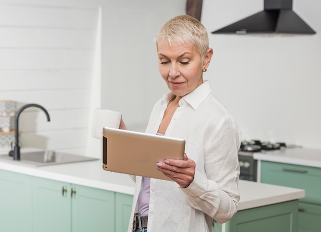 Senior woman looking on her tablet in the kitchen