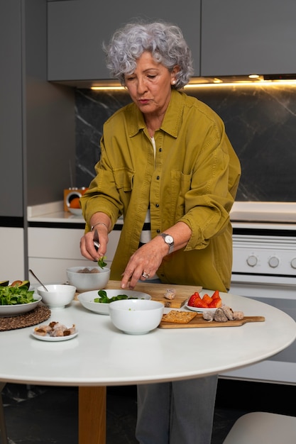 Senior woman making dish with figs in the kitchen