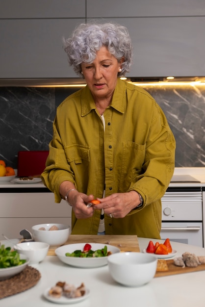 Free photo senior woman making dish with figs in the kitchen