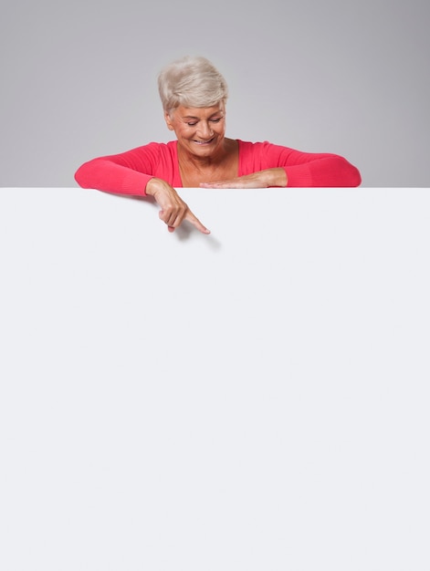 Free photo senior woman peeking on whiteboard