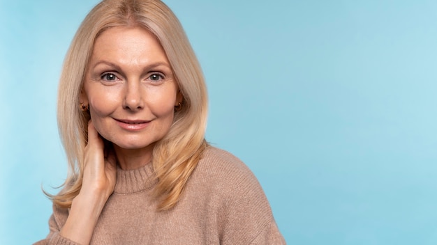 Free photo senior woman posing against a blue background