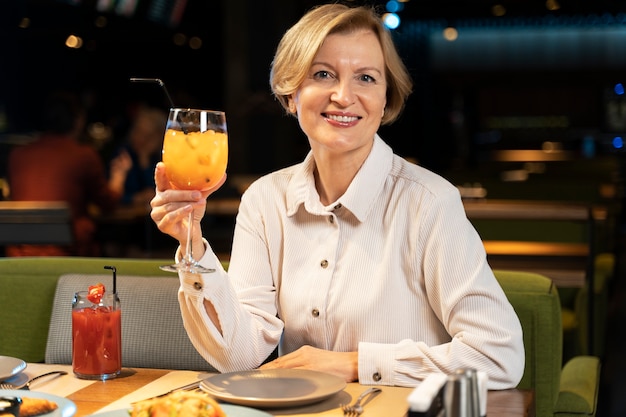 Senior woman posing with her cocktail at a restaurant