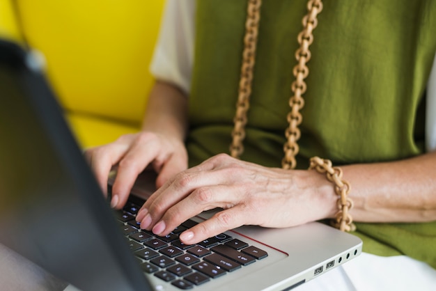 Free photo senior woman's hand on laptop keypad