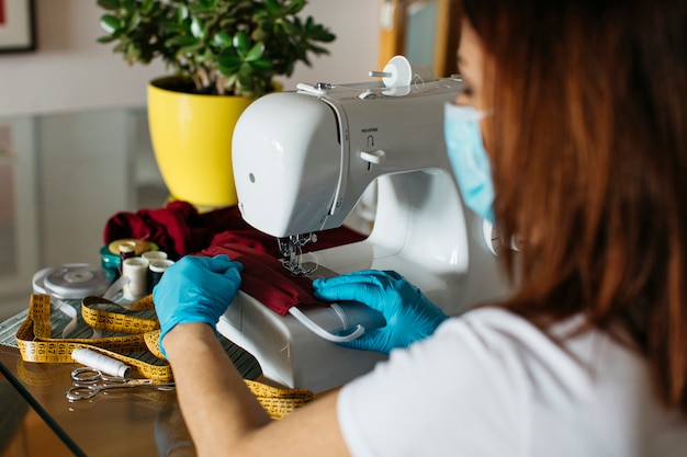 Senior woman sewing with a machine cloth face masks