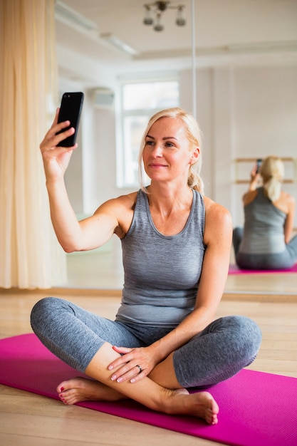 Senior woman taking a selfie on yoga mat