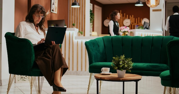 Senior woman using laptop in lobby