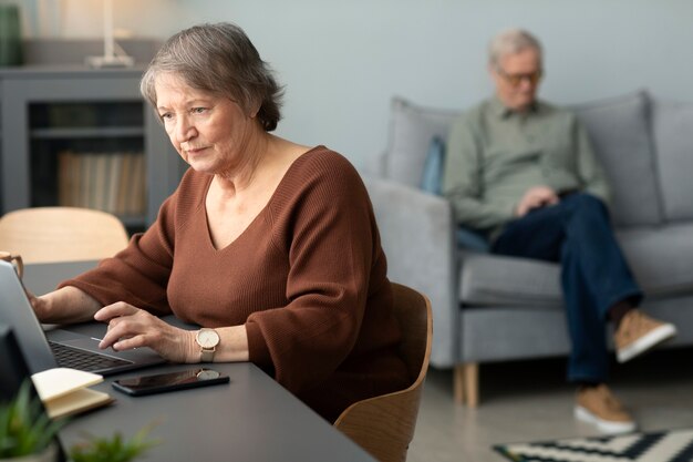 Senior woman using laptop sitting at desk in living room