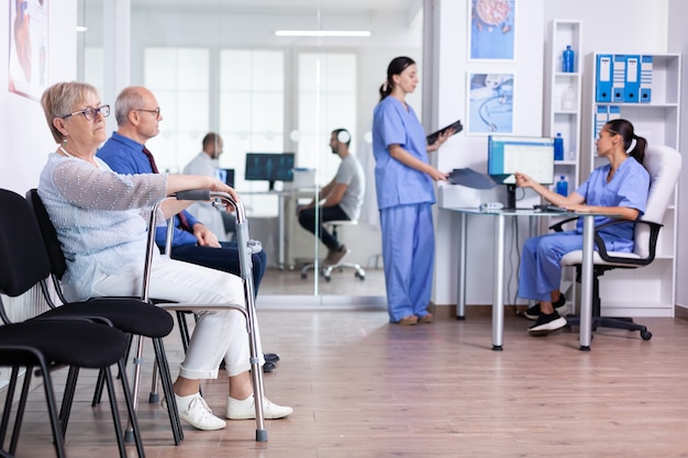 Senior woman with walking frame in hospital waiting room for rehabilitation treatment