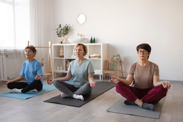 Senior women doing yoga together at home