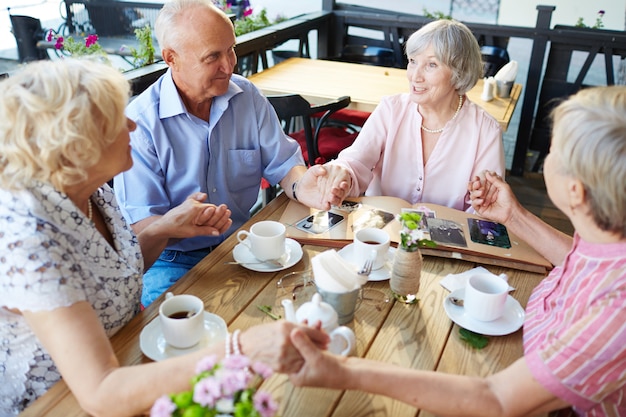 Seniors holding hands in cafe