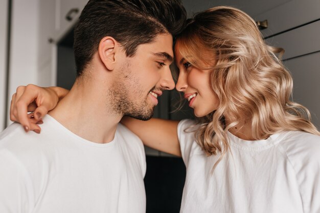 Sensual blonde girl embracing boyfriend. Pleased man looking at wife with love.