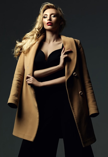 sensual glamour portrait of beautiful blond woman model lady with fresh makeup in classic black costume and overcoat