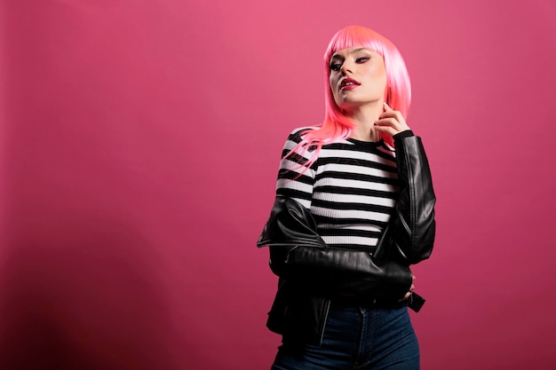 Free Photo sensual punk adult wearing rocker leather jacket in studio, expressing carefree funky fashion style. attractive beautiful lady with trendy clothes and stylish pink hair, cute makeup.