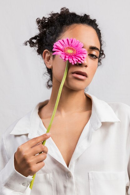 Sensual woman with flower covering eye