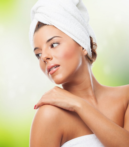 Sensual woman with towel on head holding hand on shoulder