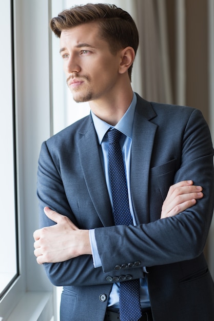 Free photo serious adult businessman looking through window