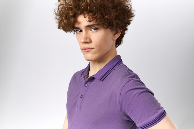 Serious attractive young Caucasian male with upright posture posing against gray background looking at camera with confidence, wearing stylish polo shirt